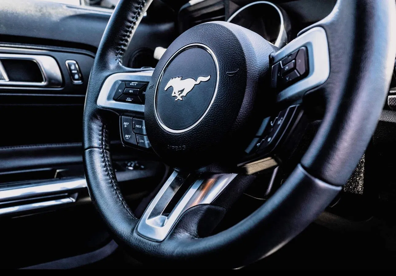 A close-up of a high-demand sports car steering wheel with premium leather interior.